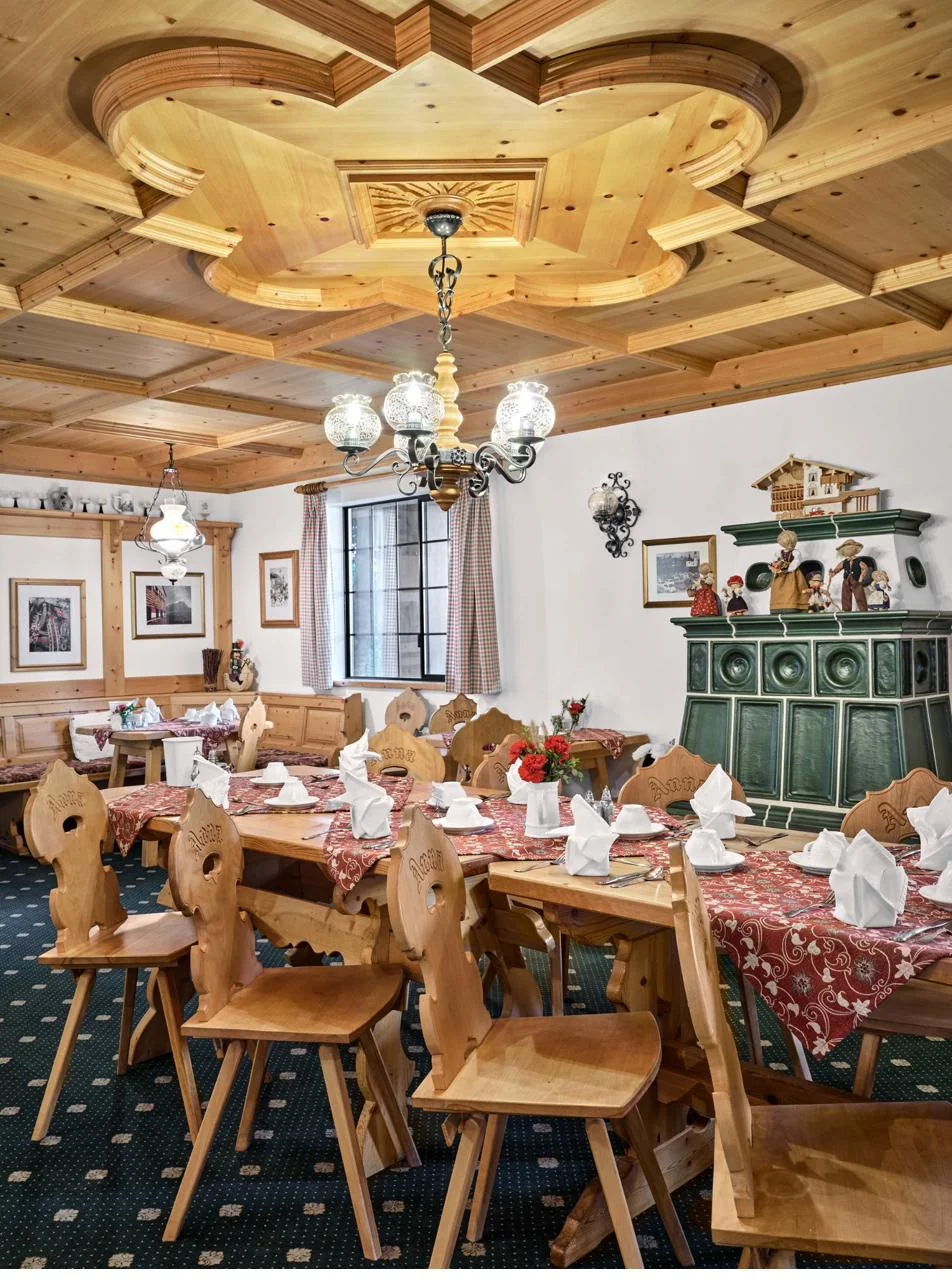 Pension Anna Stube dining room with coffered pine ceiling and green Kachelofen stove